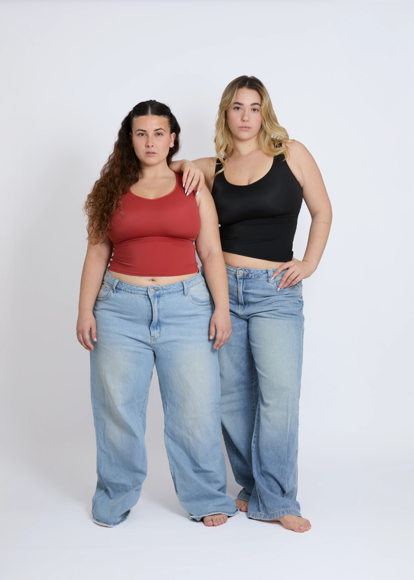Two models wearing black and brown supportive tank tops for large breasts with built-in bras, showcasing inclusive sizing and fit