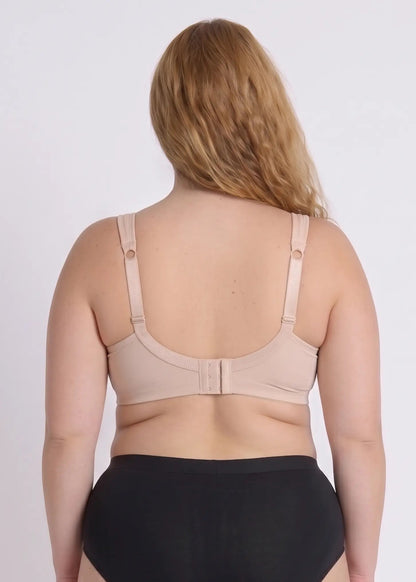 Back view of a model wearing a beige bra for full busts, showing the wide smoothing back band and adjustable comfort straps with ring details.
