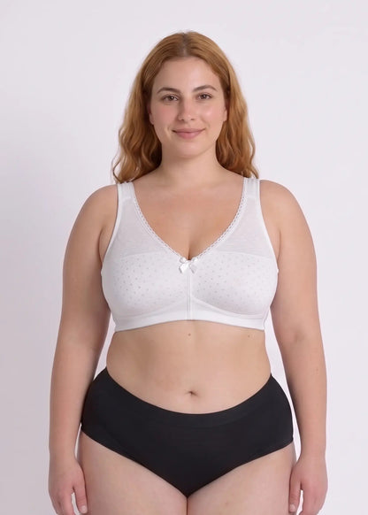 Front view of a smiling model wearing a supportive white wireless bra designed for full busts, featuring a subtle dotted pattern, lace accents, and a small center bow.