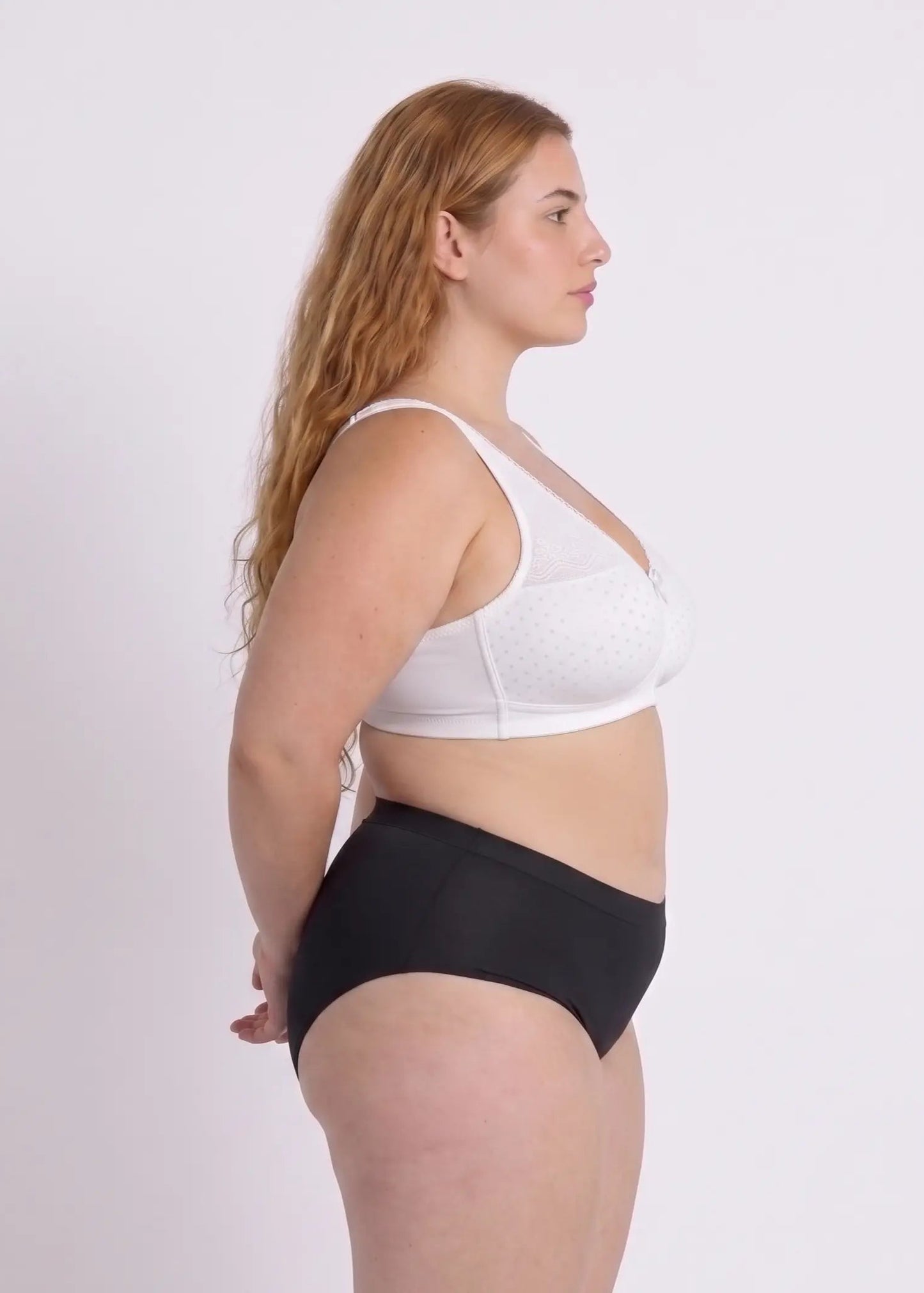 Three-quarter front view of a model wearing a white wireless bra for large busts, showcasing a subtle dotted pattern, delicate lace trim along the neckline, and natural shaping.