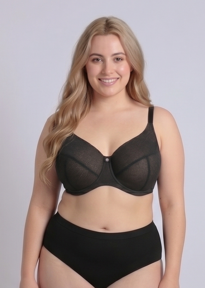 Front view of a smiling plus-size model wearing the NewG Bella black underwire minimizer bra for large busts. The image highlights the geometric patterned mesh cups, full coverage, and supportive reducing effect, against a white studio background.