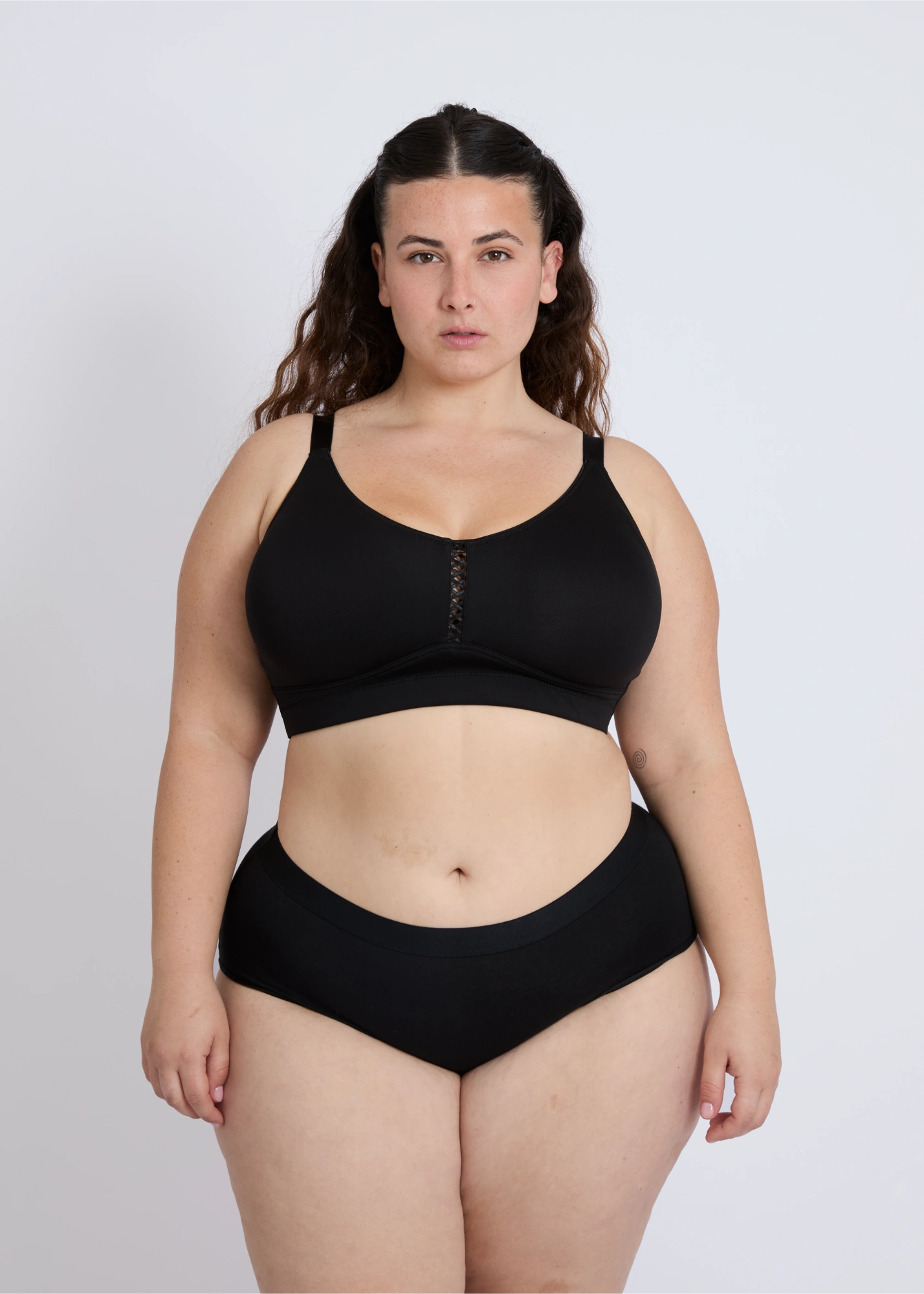 Front view of the black Joy seamless wire-free bra for large breasts on a brunette plus-size model, showcasing the smooth, seamless design and full support in a clean portrait shot