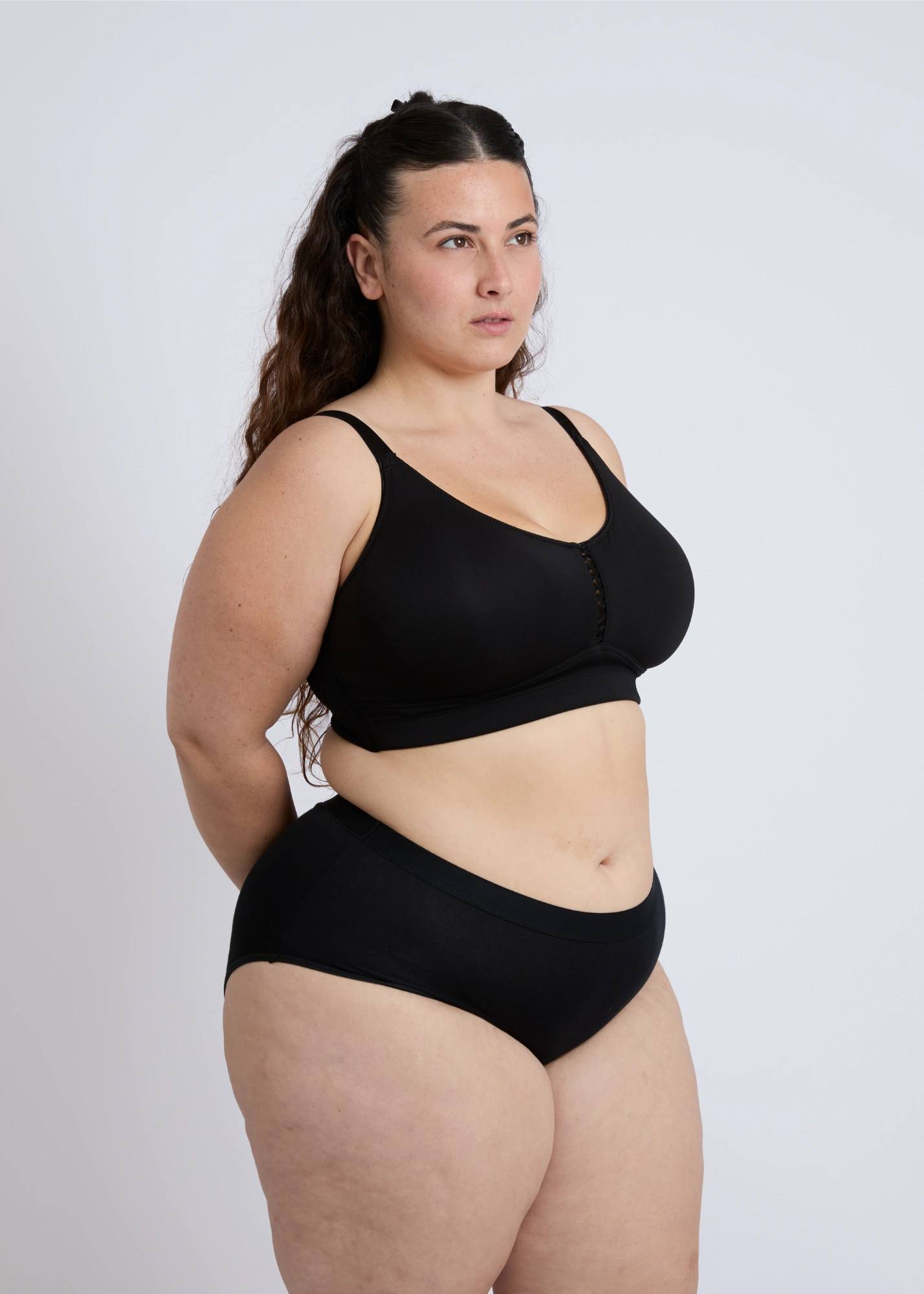Side profile view of a plus-size model wearing the black Joy seamless wire-free bra, demonstrating side support and a smooth fit for large breasts against a white background