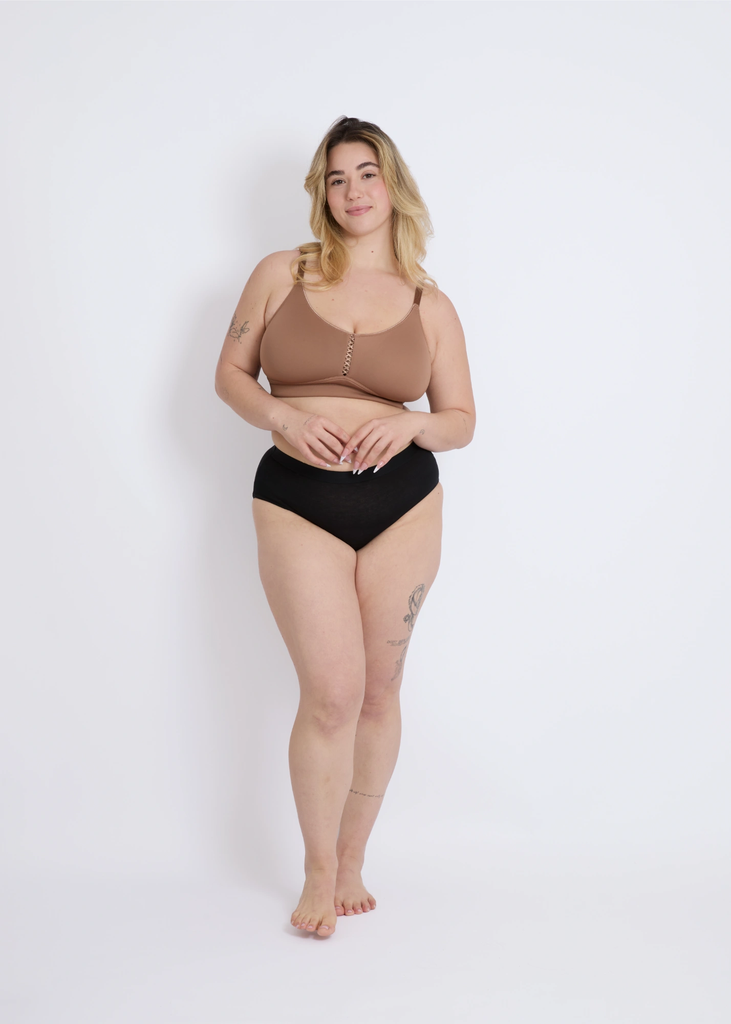 Full-body view of a plus-size model wearing the mocha brown Joy seamless wire-free bra for large breasts, demonstrating a smooth silhouette and comfortable fit against a white studio background