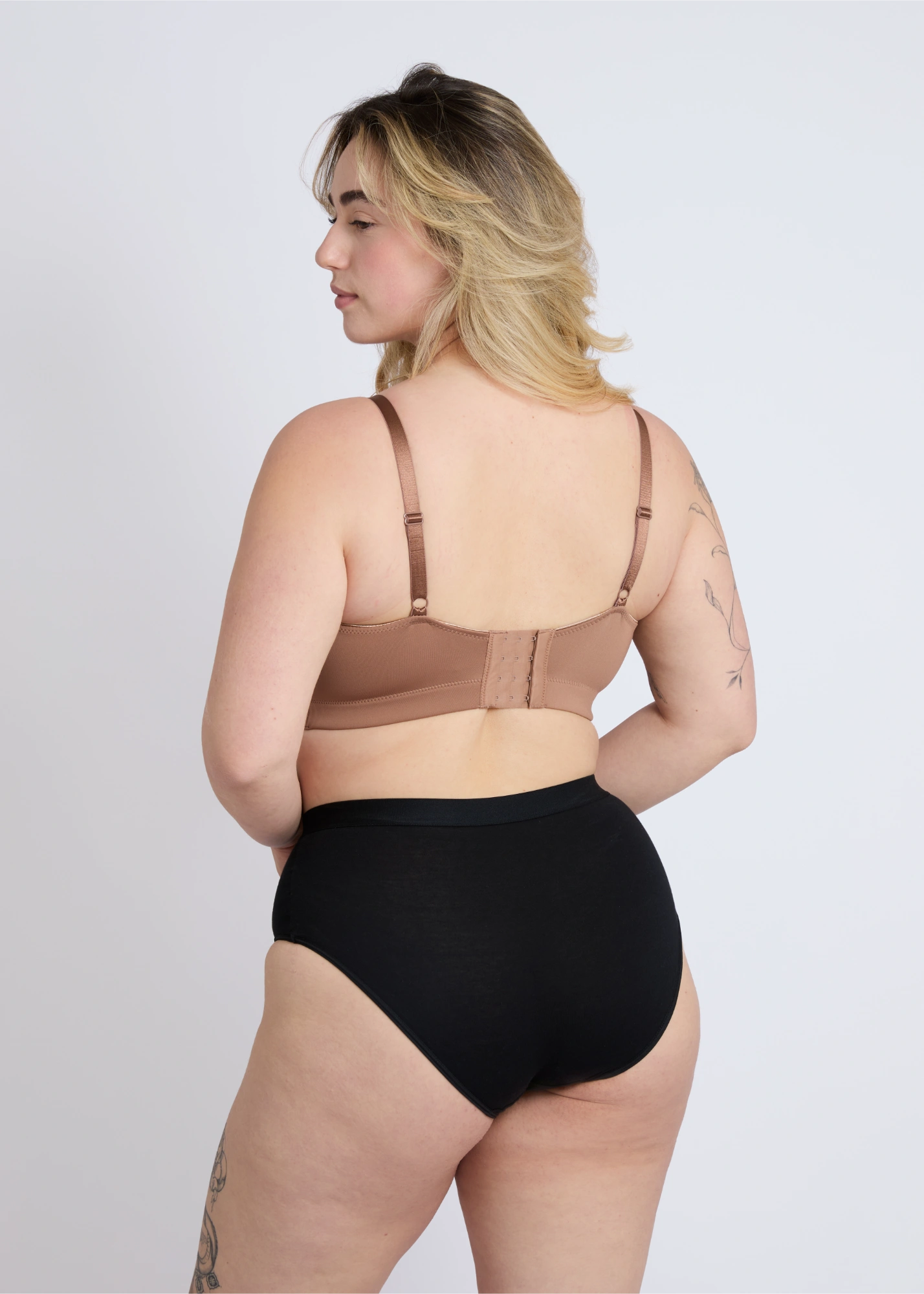 Back view of the mocha brown Joy seamless wire-free bra for large breasts on a plus-size model, highlighting the smooth back band, adjustable straps, and secure hook-and-eye closure