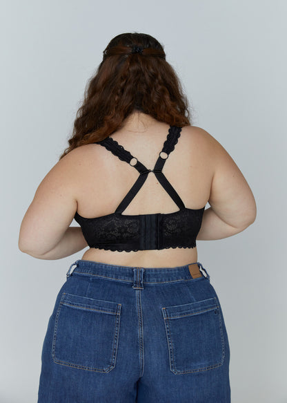 Back view of the black Kimi wire-free lace bra for large breasts on a model, showcasing the adjustable straps converted into a supportive cross-back design and wide band