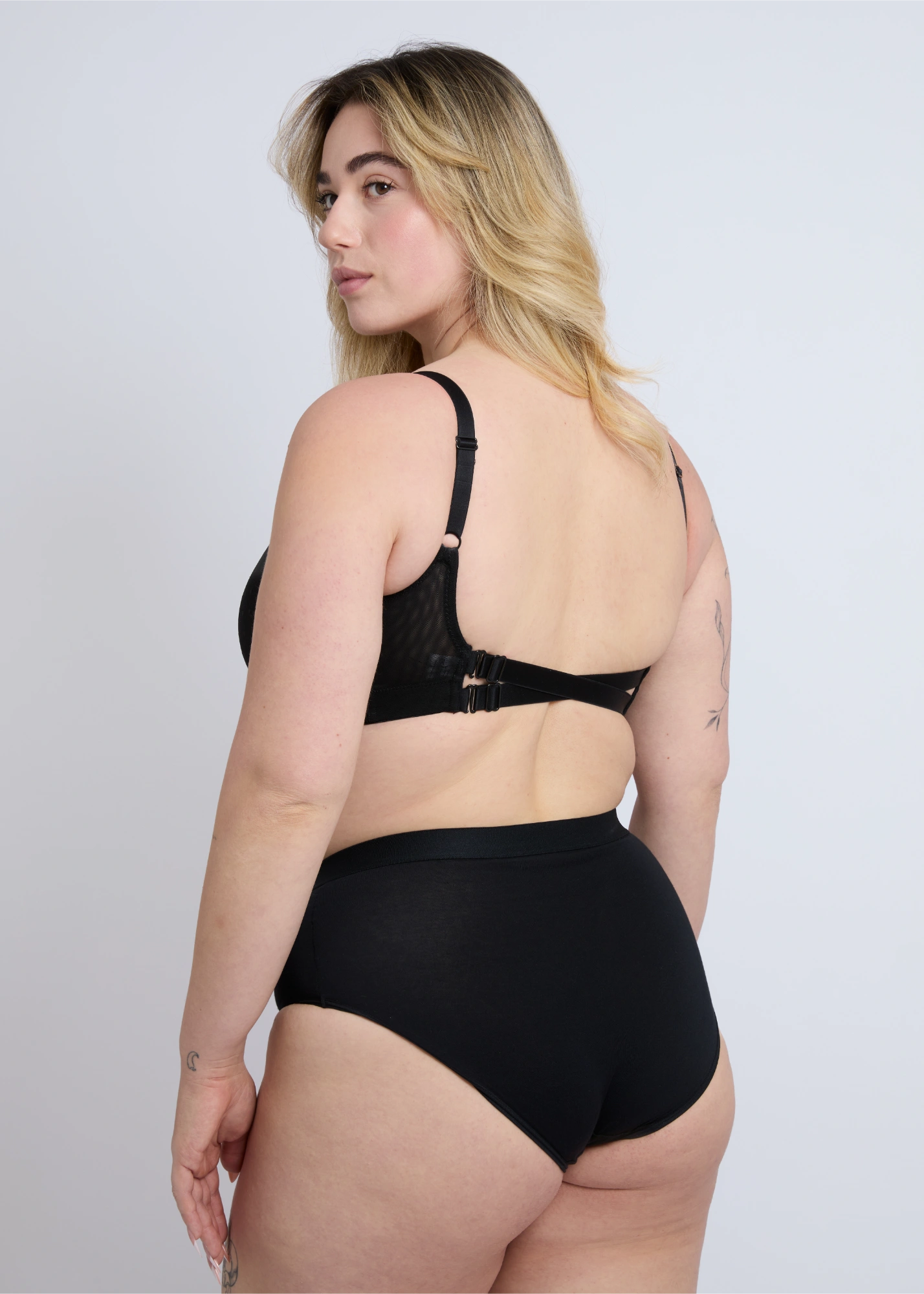 Rear view of the NewG Alma black wireless bra for large busts, highlighting the adjustable double back strap design and supportive lace mesh on a plus-size model.