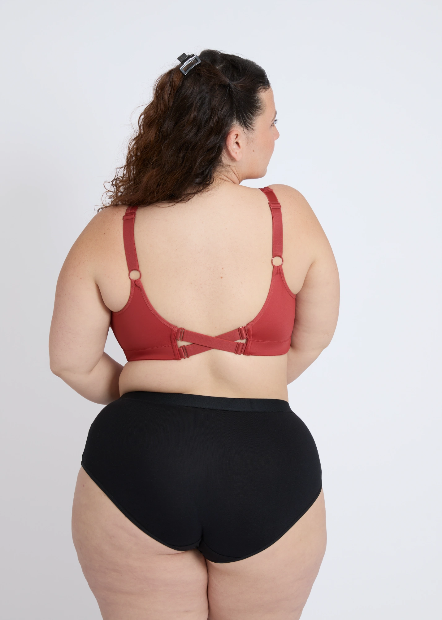 Rear view of the NewG Doni red wireless bra for large busts, showing the unique criss-cross back strap design and smooth support on a plus-size model.