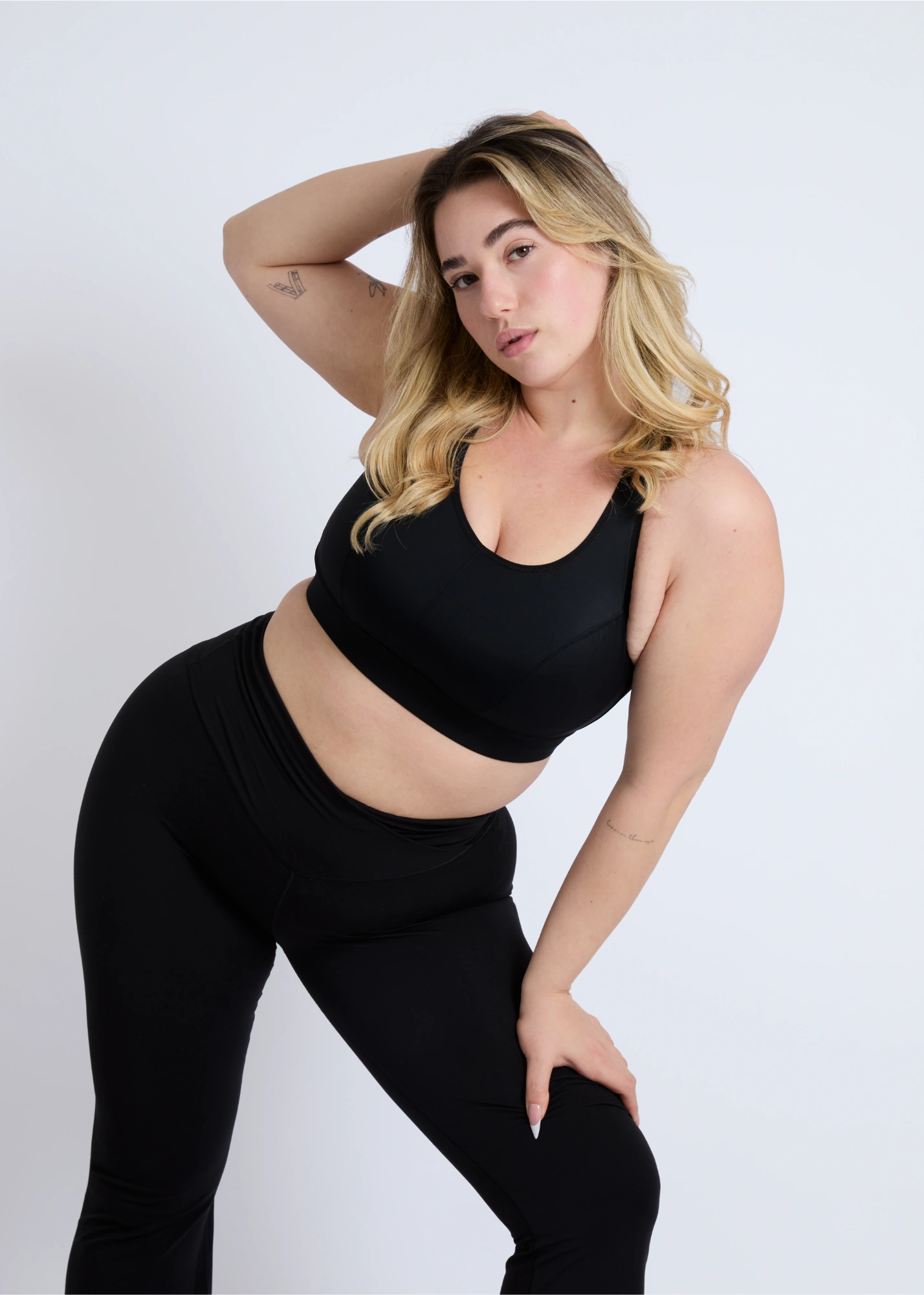 Woman with arms raised wearing a black high-impact sports bra for large breasts to show stability and support