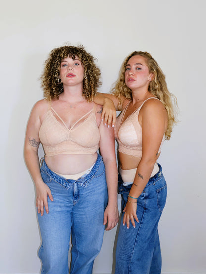 Two inclusive plus-size models with large breasts posing in matching nude (peach-toned) wire-free lace bralettes (Mia bra) and open blue jeans against a neutral background, showcasing comfort and supportive fit